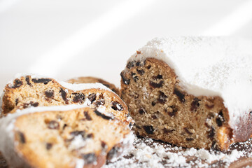 Traditional Christmas stollen made of dried fruits and nuts sprinkled with powdered sugar on the background of a Christmas decor with candles. Traditional Christmas cupcake