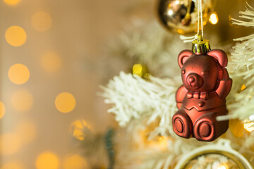 Close up of holidays location with red bear toy and garlands on white yellow Christmas tree