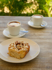 Two cups of coffee with milk with cake.