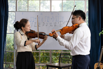 student learning how to play violin with teacher in classroom