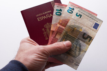 View of hand holding a Spanish passport with money. Concept of traveling or tourism or vacation.
