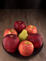 Yellow pear and red apples fruits on black plate.