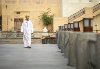 Arab man walking in the alleys of al seef district in Dubai - obrazy, fototapety, plakaty