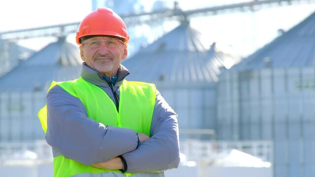 Grain elevator marine shipping. Skilled worker with beard and glasses stands against powerful warehouse with silo containers at port