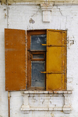 A window with iron shutters on the facade of an old building. The picture was taken in Russia, in the city of Orenburg