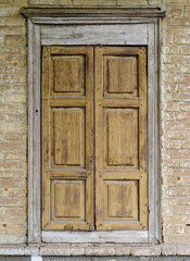 Wooden window with closed shutters on the facade of an old brick building. The picture was taken in Russia, in the city of Orenburg
