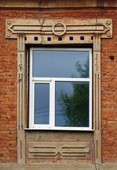 Modern plastic double-glazed windows in the window of an old brick building with stucco molding. The picture was taken in Russia, in the city of Orenburg