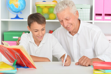 Grandfather with grandson doing homework at home