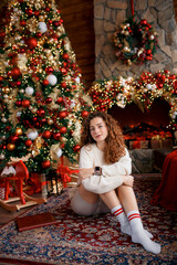 A beautiful girl portrait in a Christmas interior. Christmas tree, decorated fireplace, lots of gifts, Christmas theme. Cozy atmosphere.