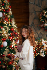 A beautiful girl portrait in a Christmas interior. Christmas tree, decorated fireplace, lots of gifts, Christmas theme. Cozy atmosphere.