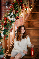A beautiful girl portrait in a Christmas interior. Christmas tree, decorated fireplace, lots of gifts, Christmas theme. Cozy atmosphere.