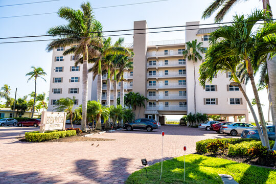 Fort Myers Beach, USA - April 29, 2018: Florida gulf coast with hotel condominium apartment building waterfront architecture and palm trees on sunny day