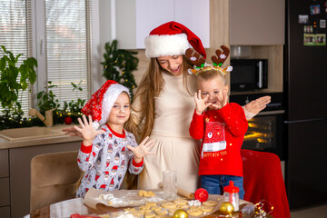 Merry Christmas. Happy Mom with children son and daughter bake Christmas cookies. Kitchen at home. Festive atmosphere