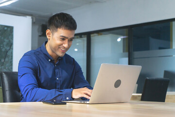 Young asian businessman executive smiling using laptop sitting at work desk in office building.