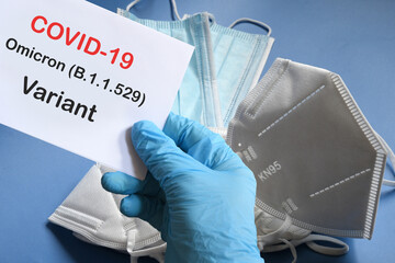 Doctor's hand in blue glove with white paper and text Covid-19 Omicron Variant with various...