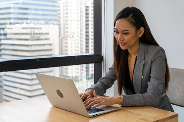 Young asian businesswoman executive smiling using laptop sitting at work desk in office building.
