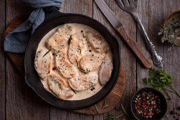 Cooked chicken breast with creamy sauce in frying pan