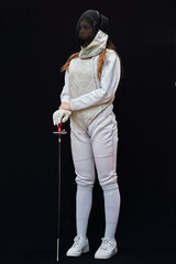 Portrait of a young fencer wearing white fencing costume and mask and holding the sword in front of...