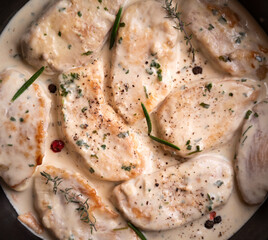 Cooked chicken breast with creamy sauce in frying pan