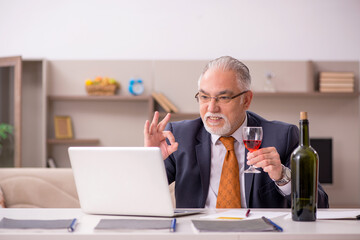 Old male employee drinking champagne at home