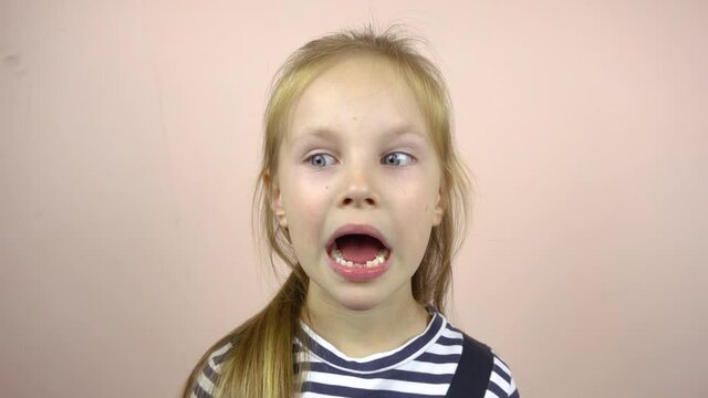 A beautiful five-six-year-old girl shows her mouth with fallen milk teeth.She smiles and grimaces.