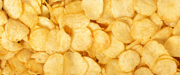 Crispy fresh potato chips, snacks background. Top view, flat lay. Banner.