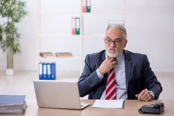 Fototapeta premium Old male employee working in the office