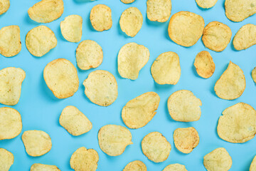 Ready fresh potato chips on a blue background. Top view, flat lay.