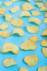 Ready fresh potato chips on a blue background. Top view, flat lay.
