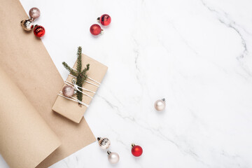 Gift, wrapping craft paper, spruce branches on a marble background. Top view, flat lay.