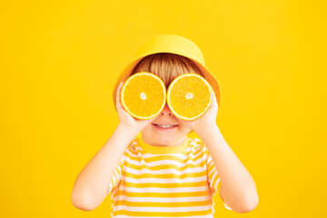 Happy child holding slices of orange fruit like sunglasses