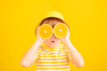 Surprized child holding slices of orange fruit like sunglasses