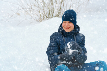 a boy plays snowballs outside, beautiful winter weather and white snow around