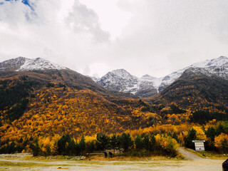Snowy mountain peak winter panorama landscape. Autumn forest at the foot of the mountains.