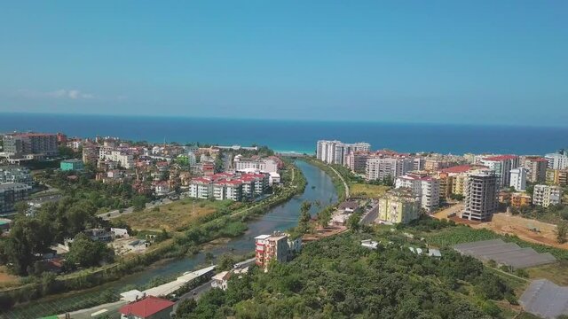 The view from the drone. Clip. View of the blue clear ocean near the resort area with a swimming pool and houses .