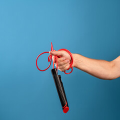 Go in for sports, jump rope, the benefits of movement for health, concept. A man's hand holds a rope in his fist, blue background