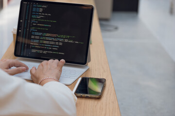 A freelance programmer works remotely, a young woman sits at a table in a coworking or business...