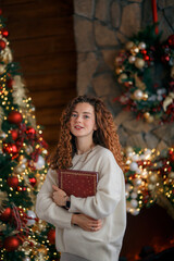 A beautiful red-haired girl portrait in a Christmas interior. Christmas theme. Cozy atmosphere. Christmas tree, decorated fireplace, lots of gifts, 