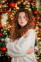 A beautiful red-haired girl portrait in a Christmas interior. Christmas theme. Cozy atmosphere. Christmas tree, decorated fireplace, lots of gifts, 
