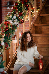 A beautiful red-haired girl portrait in a Christmas interior. Christmas theme. Cozy atmosphere. Christmas tree, decorated fireplace, lots of gifts, 