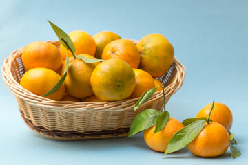 tangerines in wicker basket on blue background