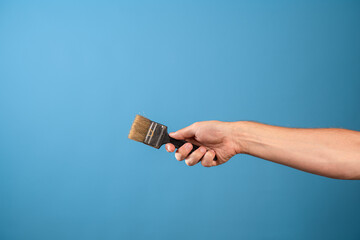 Update the interior, paint the walls, decor in the house. A man's hand stretches out a paint brush,...