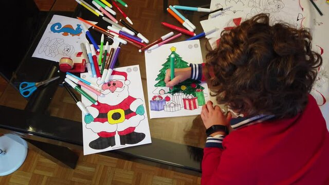 Boy child 7 years old draws  Santa Claus and the tree - preparation and decorations for Christmas 2021 - year of epidemic due to Covid-19 Coronavirus lockdown