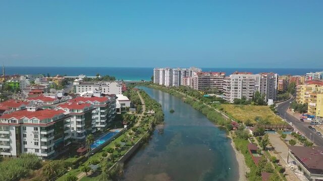 The view from the drone. Clip. View of the blue clear ocean near the resort area with a swimming pool and houses .