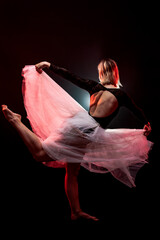 ballerina with a white dress and black top posing on red smoke background © Nikola Spasenoski