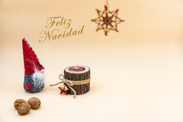 Postal navideña con texto en español Feliz Navidad y fondo beige, nueces, vela de madera y un...