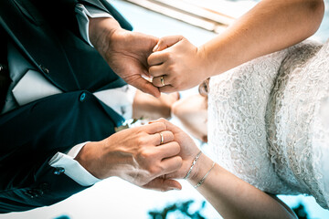 Fototapeta premium Joined hands of newlyweds capturing wedding rings. A kiss can be seen in the background. The hands of the newlyweds on which the wedding rings can be seen 