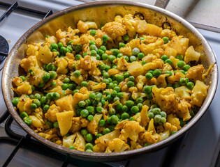 A delicious spicy north Indian vegetarian dish containing cauliflower, potatoes, peas and corriander. Freshly cooked in a frying pan.