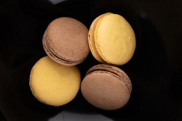 Several sweet macaroons on a ceramic plate, close-up, top view.