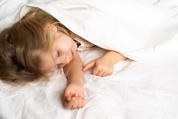 A little blonde is sleeping sweetly in a bed with white underwear. space for the text. healthy sleep of the child